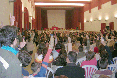 Asistentes con libros para firmar por la autor levantan la mano