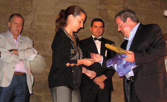  El presidente del Patronato entrega un pin de la bandera de Alhama  a la representante del Ayuntamiento en el Acto, Sonia Jiménez 