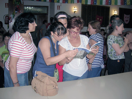 Unas vecinas hojean el libro, tras la presentación